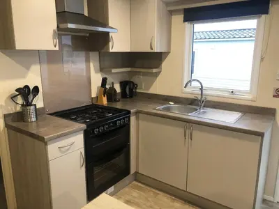 a small kitchen with a stove and a sink at Luxury 3 bedroom caravan between Perranporth and Newquay, Cornwall in Newquay