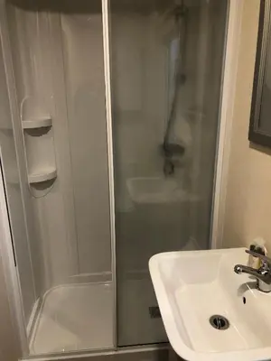 a shower with a glass door next to a sink at Luxury 3 bedroom caravan between Perranporth and Newquay, Cornwall in Newquay