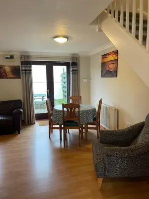 a living room with a table and chairs and a staircase at Rose Cottage in Camelford