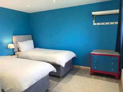 a room with two beds and a blue wall at Kingfisher Glamping Cabin in Bodmin