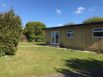 a small wooden house with a grass yard at Kingfisher Glamping Cabin in Bodmin