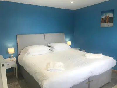 a blue bedroom with a large bed with white pillows at Kingfisher Glamping Cabin in Bodmin