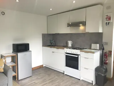 a kitchen with white cabinets and a stove top oven at Kingfisher Glamping Cabin in Bodmin