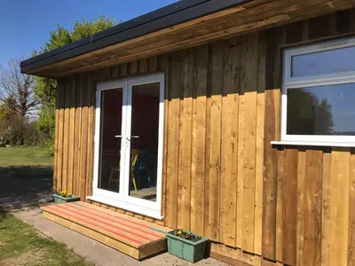 a wooden building with a porch and a window at Woodpecker Glamping Cabin in Bodmin