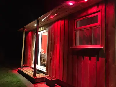 a house with red lights on the side of it at Woodpecker Glamping Cabin in Bodmin
