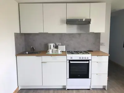 a white kitchen with a stove and a sink at Woodpecker Glamping Cabin in Bodmin