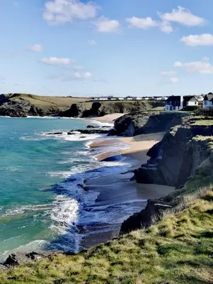 a beach with rocks and the ocean and houses at Toms Hut and Robins Rest Shepherd Huts near Wadebridge in Wadebridge