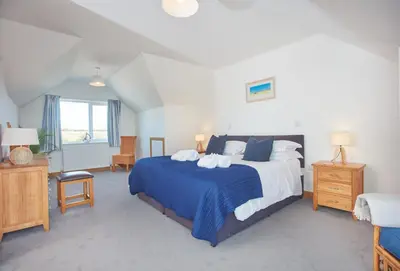 a bedroom with a large bed with a blue blanket at Seawynds in Port Isaac
