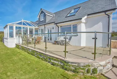 a house with a deck with a table and chairs at Seawynds in Port Isaac
