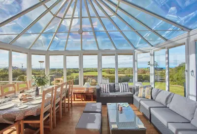 a conservatory with a glass roof with a table and chairs at Seawynds in Port Isaac