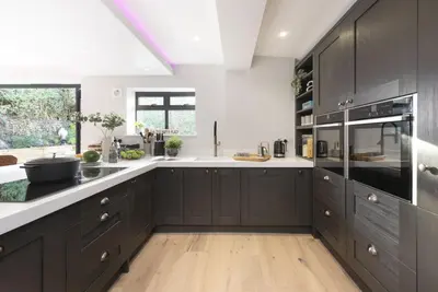 a kitchen with dark brown cabinets and white counter tops at Chy An Eglos - Private pool and Hot tub in Carbis Bay