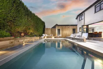 a swimming pool with chairs next to a house at Chy An Eglos - Private pool and Hot tub in Carbis Bay