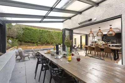 an outdoor patio with a wooden table and chairs at Chy An Eglos - Private pool and Hot tub in Carbis Bay