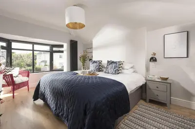 a bedroom with a large bed and a chair at Chy An Eglos - Private pool and Hot tub in Carbis Bay