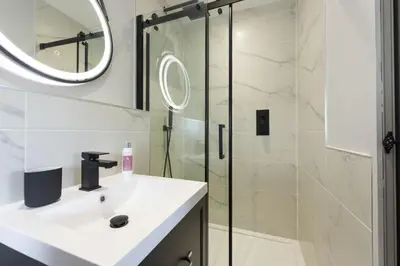 a bathroom with a sink and a shower with a mirror at Chy An Eglos - Private pool and Hot tub in Carbis Bay