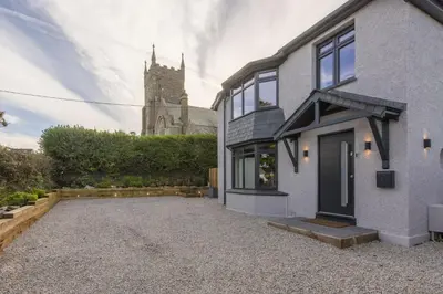 a house with a church in the background at Chy An Eglos - Private pool and Hot tub in Carbis Bay