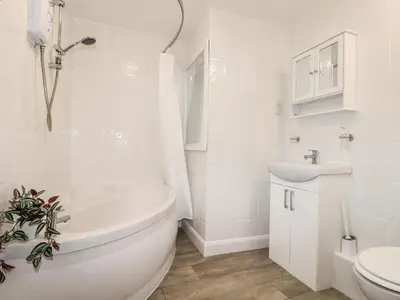 a white bathroom with a tub and a sink at The Old Bark House No 3 in Mevagissey