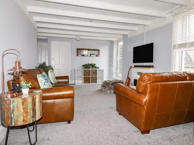 a living room with brown leather furniture and a flat screen tv at The Old Bark House No 3 in Mevagissey