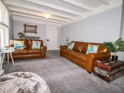 a living room with two brown leather couches at The Old Bark House No 3 in Mevagissey