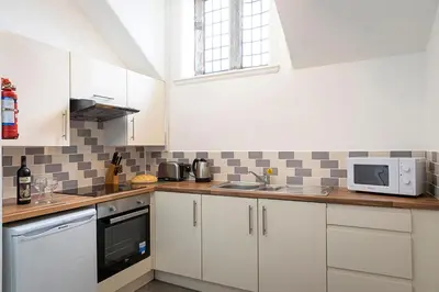 a kitchen with white cabinets and a sink and a microwave at Hengar Manor Apartments in Michaelstow