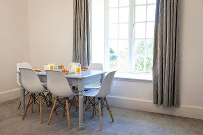 a dining room table with chairs and a window at Hengar Manor Apartments in Michaelstow