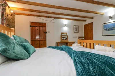 a bedroom with a white bed with green pillows at South Boduel Farmhouse in Liskeard