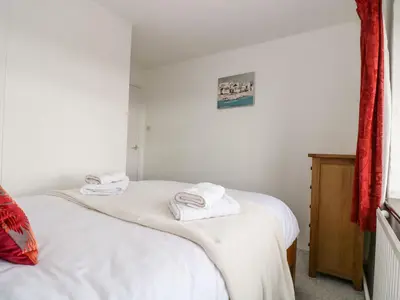 two beds in a room with white sheets and towels at South Boduel Farmhouse in Liskeard
