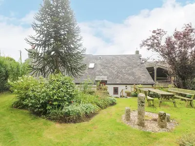 a cottage with a picnic table and a bench at South Boduel Farmhouse in Liskeard