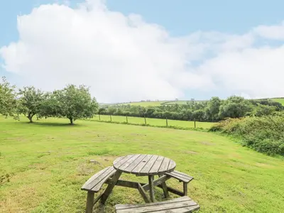 a wooden picnic table sitting in a field at South Boduel Farmhouse in Liskeard