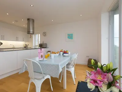 a white kitchen with a table and chairs in a room at The Lighthouse in St Ives