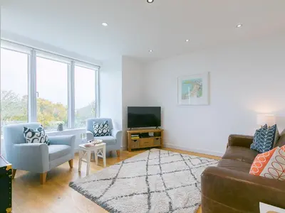 a living room with a couch and two chairs and a tv at The Lighthouse in St Ives