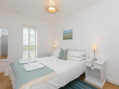 a white bedroom with a bed and a window at The Lighthouse in St Ives