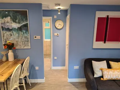 a living room with a table and a clock on the wall at Pebble Cottage in Uny Lelant