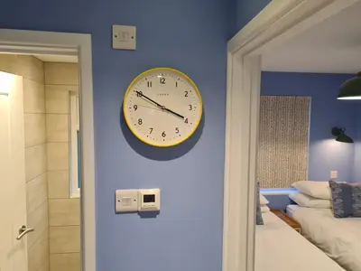 a clock on a blue wall in a bedroom at Pebble Cottage in Uny Lelant