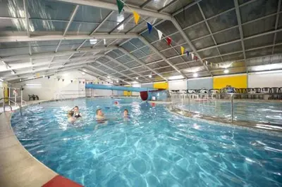 a group of people swimming in a swimming pool at Pebble Cottage in Uny Lelant