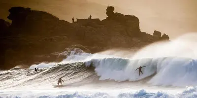 a painting of two surfers riding a wave in the ocean at Pebble Cottage in Uny Lelant
