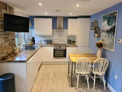 a kitchen with a wooden table and chairs at Pebble Cottage in Uny Lelant