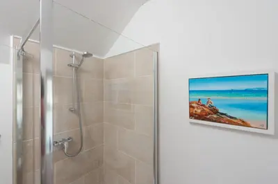 a bathroom with a shower and a tv on the wall at Laity Vean Hideaway - 2 Pets Allowed - Free Parking & WiFi in Carbis Bay