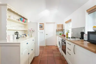 a kitchen with white cabinets and a tile floor at Laity Vean Hideaway - 2 Pets Allowed - Free Parking & WiFi in Carbis Bay