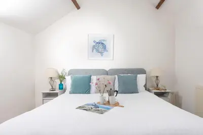 a bedroom with a large white bed with blue pillows at Laity Vean Hideaway - 2 Pets Allowed - Free Parking & WiFi in Carbis Bay