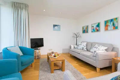 a living room with two chairs and a couch and a tv at Puffins in St Ives