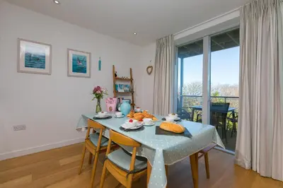 a dining room with a blue table and chairs and a window at Puffins in St Ives