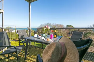 a table and chairs on a deck with a view of the ocean at Puffins in St Ives