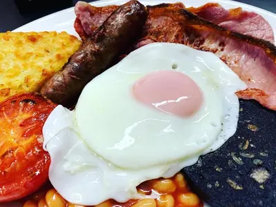 a plate of breakfast food with eggs sausage and bacon at The Cottage Bed & Breakfast in Polperro
