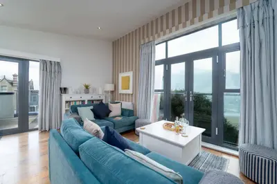 a living room with a blue couch and a large window at Porthminster Mews in St Ives