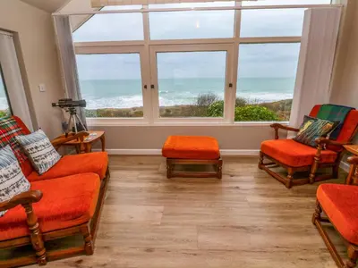a living room with orange chairs and a large window at Stonecroft in Praa Sands