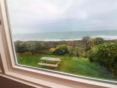 a window with a picnic table looking out at the ocean at Stonecroft in Praa Sands