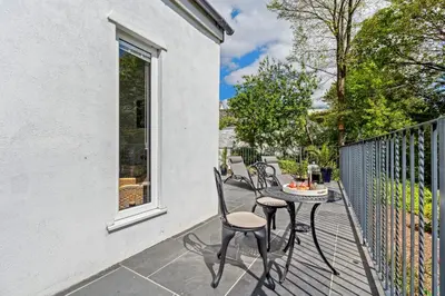 a patio with chairs and a table on a balcony at Trewethen Cottage Barn 1 near Port Isaac in Port Isaac