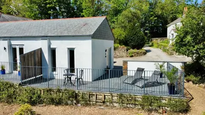 a house with three chairs on a deck at Trewethen Cottage Barn 1 near Port Isaac in Port Isaac