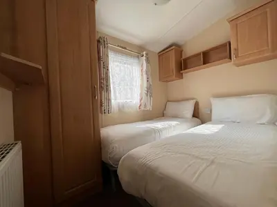 a small bedroom with two beds and a window at Contemporary Caravan at Newquay Holiday Park in Newquay